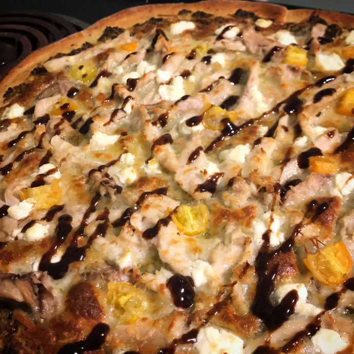 Pesto, chicken, grape tomato, goat cheese pizza with a balsamic drizzle