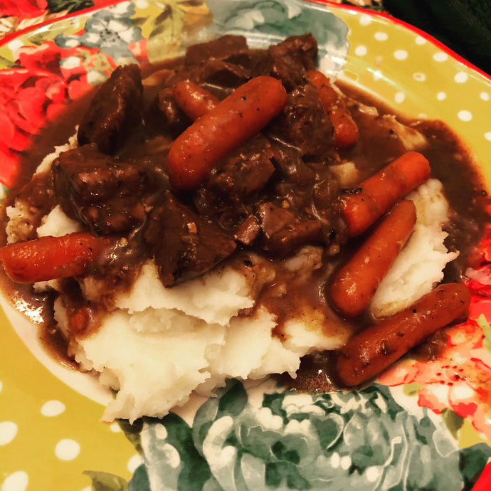 Slow braised beef tips and baby carrots in gravy over a bed of creamy whipped potatoes